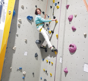 Frau beim Klettern an einer Kletterwand in einer Halle